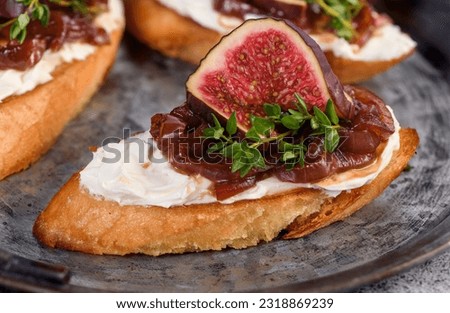 Canape or crostini with toasted baguette, cream cheese, onion jam, figs and fresh thyme on a tin tray. Ideal appetizer as an aperitif. Royalty-Free Stock Photo #2318869239