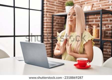 Young blonde woman having video call using deaf language at home