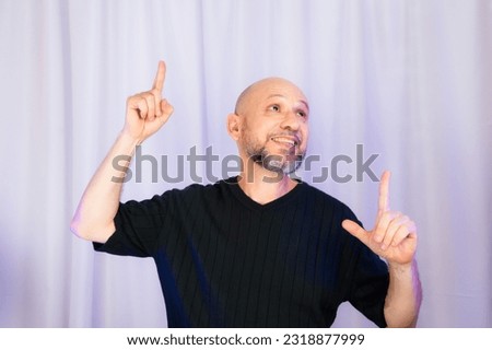 Bearded and bald man making various signs with his hands. Isolated on gray color background.