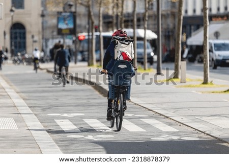 A mother on a bicycle with her child on a baby carrier. Royalty-Free Stock Photo #2318878379
