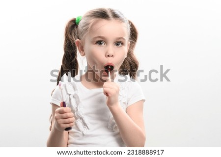 little girl licks lollipop and holds toothbrush on white background, copy space, photo idea for dentist.