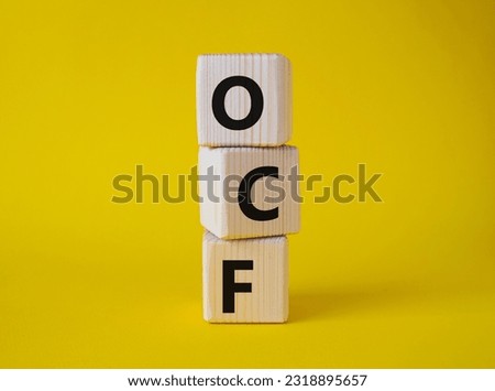 OCF - Operating Cash Flow symbol. Wooden cubes with words OCF. Beautiful yellow background. Business and OCF concept. Copy space.