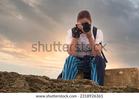 Redhead with camera and backpack on the edge of the ocean