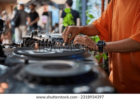 Hip hop DJ playing music on a summer festival. Hands of a club disc jockey mixing musical tracks on a party.  Royalty-Free Stock Photo #2318934397
