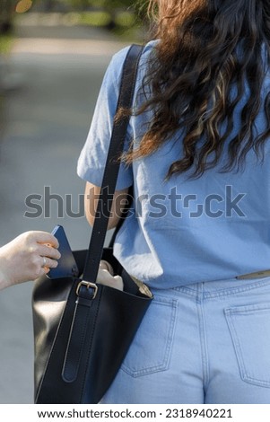 Thief stealing a cell phone from a woman's purse bag Royalty-Free Stock Photo #2318940221