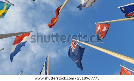 Look up view to the row of flags attached to the poles, over blue sky background