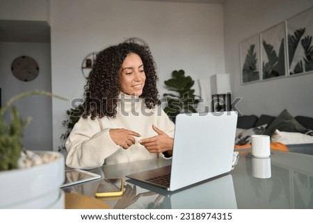 Young woman, female latin employee using laptop remote working at home office looking at computer talking having hybrid virtual meeting learning english communicating by video call, elearning webinar. Royalty-Free Stock Photo #2318974315