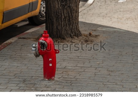 A red fire hydrant stands next to the roadway so that in case of a fire, a fire truck can quickly connect to fill water into the extinguishing tank. Сoncept of good communications design for services