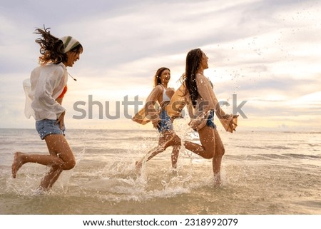 Group of Young Asian woman friends walking and playing together in the sea at tropical island beach at summer sunset. Attractive girl enjoy and fun outdoor lifestyle travel nature on holiday vacation. Royalty-Free Stock Photo #2318992079