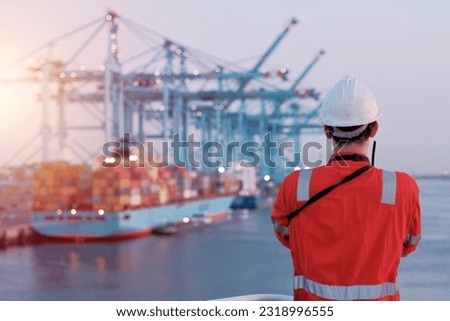 Offshore technician. Seafarer. Seaman. Navigator. A man in a boiler suit is standing in front of the port. Seafarer in front of the container terminal. Royalty-Free Stock Photo #2318996555