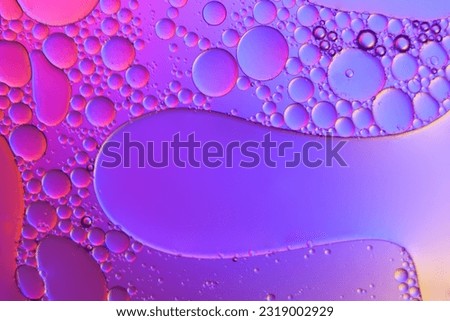 Top view movement of oil bubbles in the liquid. Oil surface multicolored background. Fantastic structure of colorful bubbles. Colorful artistic image of oil drop floating on the water