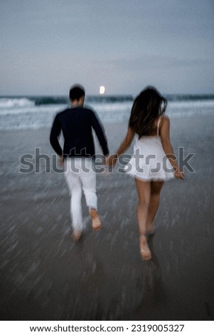 Couple running along beach at sunset motion blur noise effect