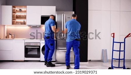 Delivery And Install Of Refrigerator Appliance. Mover Carrying Fridge Royalty-Free Stock Photo #2319029371