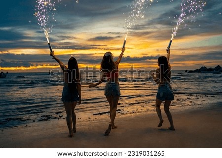 Group of Young Asian woman friends playing sparklers firework together at tropical island beach in summer night. Attractive girl enjoy and fun outdoor lifestyle beach party on holiday travel vacation. Royalty-Free Stock Photo #2319031265