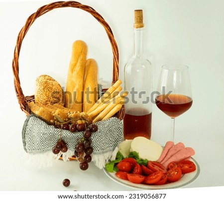 isolated picnic basket straw bread varieties healthy nutrition red wine glass fruit baguette bread plaid cotton cover grape tomatoes greens cheese plate salami cocktail invitation entertainment event 