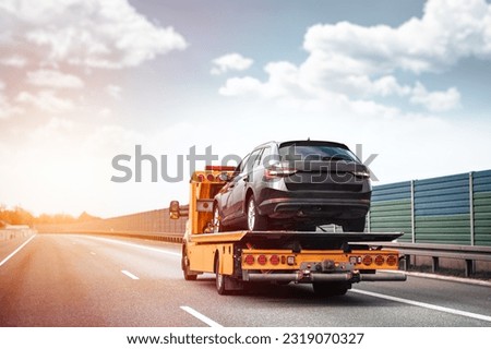 Reliable Towing and Recovery Services: 24-7 Assistance for Vehicle Breakdowns and Accidents. Emergency roadside assistance on the highway. side view of the flatbed tow truck with a damaged vehicle Royalty-Free Stock Photo #2319070327