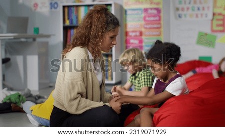 Young teacher cheering and calming upset African-American girl in kindergarten. Female teacher hug and comfort sad kid in nursery school Royalty-Free Stock Photo #2319071929