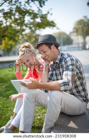 trendy young couple listening music on a digital tablet in the street