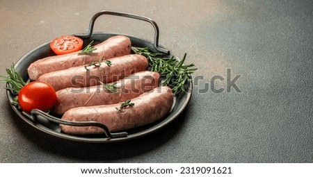 Raw sausages and ingredients on the grill pan ready to cook. Grilling food, bbq, barbecue. Long banner format. top view, Royalty-Free Stock Photo #2319091621