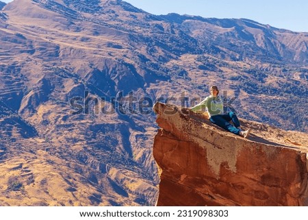 Girl tourist on an extreme ledge in the rock Troll tongue. View of the Caucasus Range, Dagestan. Royalty-Free Stock Photo #2319098303