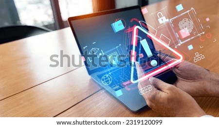 Hands of businessman using smartphone and laptop in office with double exposure of triangle caution malware warning icon hologram. Scam virus spyware malware antivirus cyber crime hack password