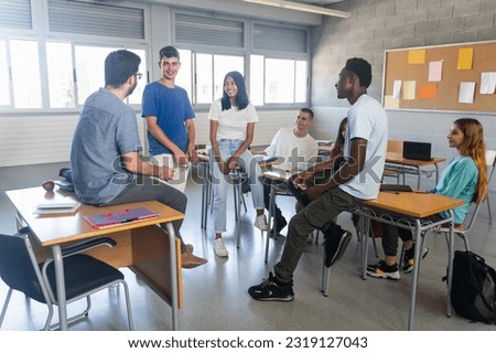 Students and young teacher having a conversation at classroom Royalty-Free Stock Photo #2319127043