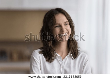 Head shot of beautiful calm woman standing alone in kitchen smile looking aside enjoy daydreaming on weekend at own or rented house. Millennial generation person portrait, happy mood and aspirations