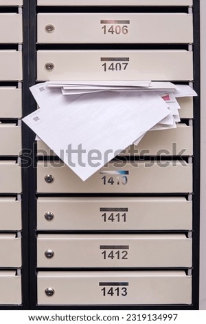 Mail boxes with overflowing documents and bills. Mailboxes with letters in the entrance of an apartment building Royalty-Free Stock Photo #2319134997