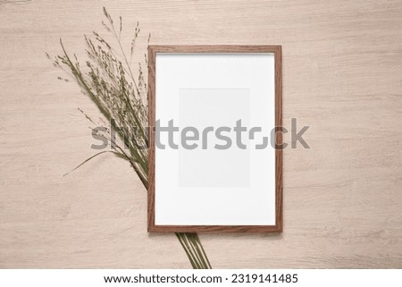 Empty photo frame and beautiful wildflowers on wooden background, flat lay. Mockup for design