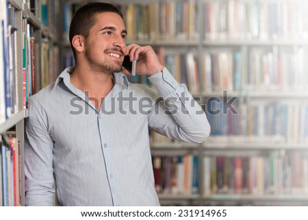 Male Student Talking On The Phone In Library - Shallow Depth Of Field