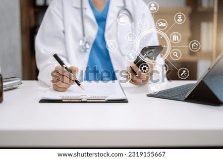 Physician or practitioner in room writing on blank notebook and work on laptop computer, smartphone on the desk,  Medic tech concept.