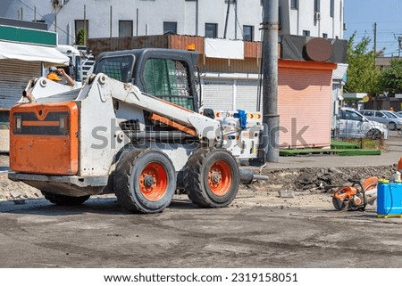 On the repaired section of the carriageway, compact and powerful construction equipment is parked along with a petrole cutter. Copy space.