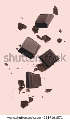 Pieces of chocolate bar falling on beige background Royalty-Free Stock Photo #2319161871