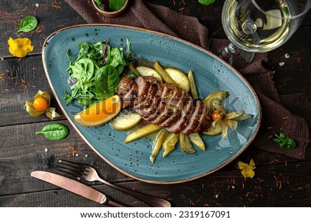 Duck breast steak with fruit. Duck fillet, apple, orange, mango and orange sauce. Menu for a restaurant. Beautiful composition on wooden boards.