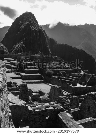 Machu Picchu in Peru on a clear sunny day, with Inca buildings and mountains in the background.