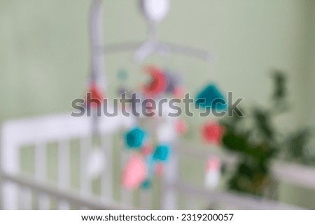 Blurred photo. Toys above the baby crib. Baby crib mobile with stars, clouds and moon.