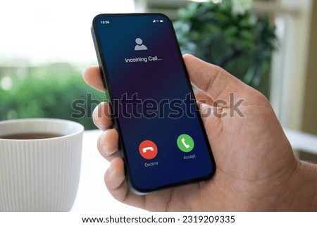 man hand holding phone with incoming call on screen in a cafe Royalty-Free Stock Photo #2319209335
