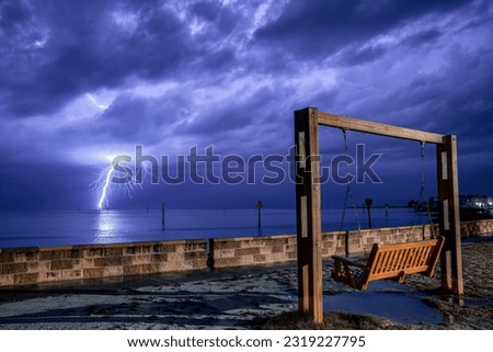 Lightning strike over water in front of swing.