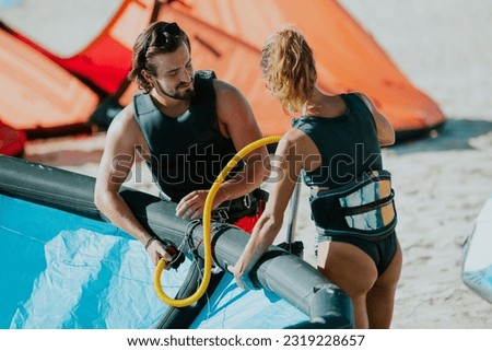 Kitesurfers couple inflating kite on beach ready to use it at sea - concept of sporty people and summer sport activity Royalty-Free Stock Photo #2319228657