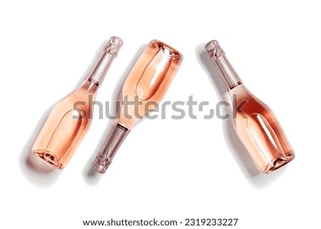 Three bottles of rose sparkling wine, set full glass champagne bottles close up, isolated on white background, cutout design object, sunlight, shadow. Summer alcoholic drinks rose wine, top view Royalty-Free Stock Photo #2319233227