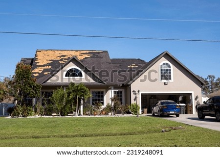 Damaged house roof with missing shingles after hurricane Ian in Florida. Consequences of natural disaster Royalty-Free Stock Photo #2319248091