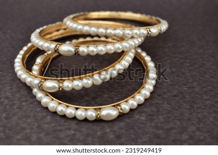 A closeup selective focus picture of a Gold bangles with Pearls worn by Indian women