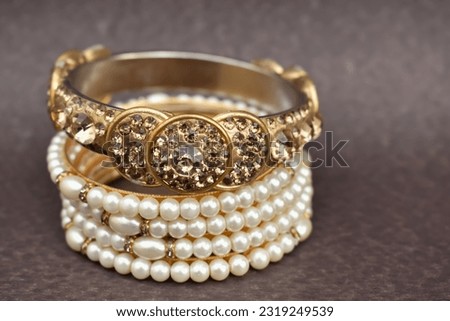 A closeup selective focus picture of a Gold bangles with Pearls worn by Indian women