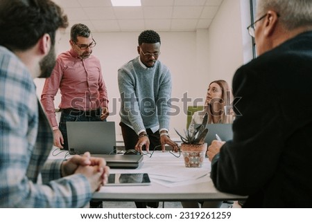 Work employee trying to get everyone’s attention and show them something on the table at the office Royalty-Free Stock Photo #2319261259