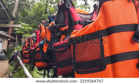 Bright orange marine life vest signal jackets close up hanging on hanger, safety on water tourism activity and watersports Royalty-Free Stock Photo #2319264767