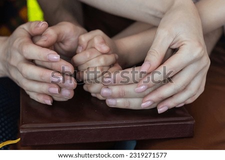 Top view of parents and kid holding empty hands together at wooden table, space for text. Family day