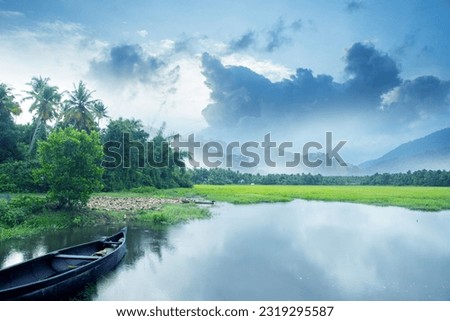 Beautiful backwater photograph with overcast sky, little wooden boat on the backwater and hills away.