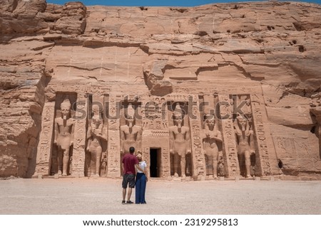 Young couple embraced, on their backs, enjoying the temple of Abu Simbel on her trip through Egypt. Temple of Queen Nefertari. Royalty-Free Stock Photo #2319295813