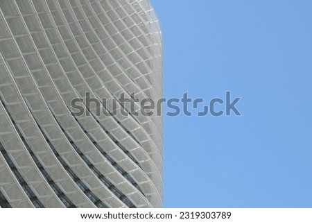 Modernist architecture with soft rounded lines, minimal architecture. Metallic wave details of the building against light blue sky.