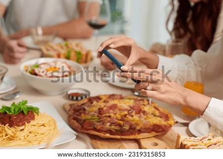 Hands of woman taking pictures of food on dinner table